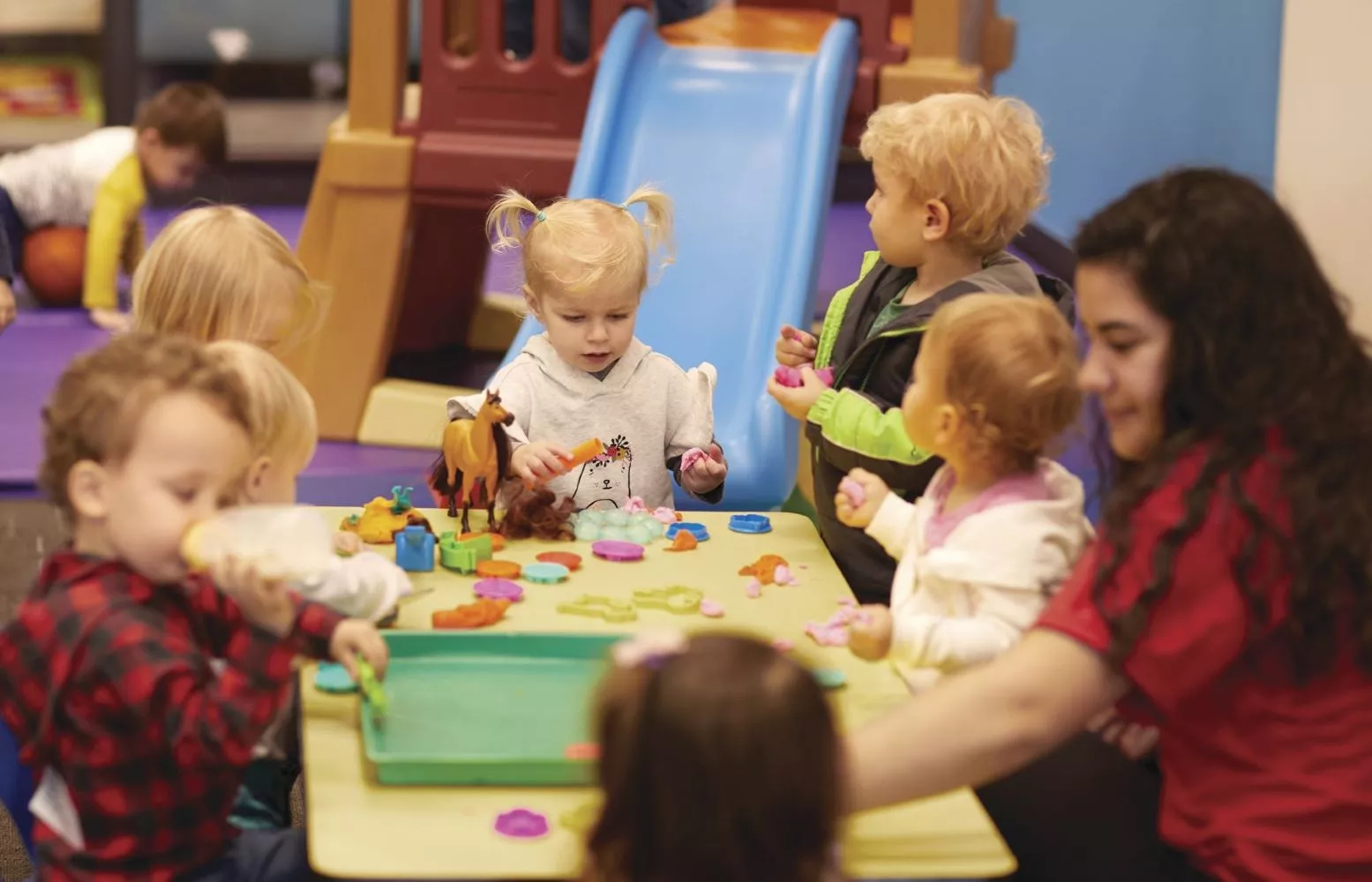 Group of toddlers supervised while playing with toys on a table.