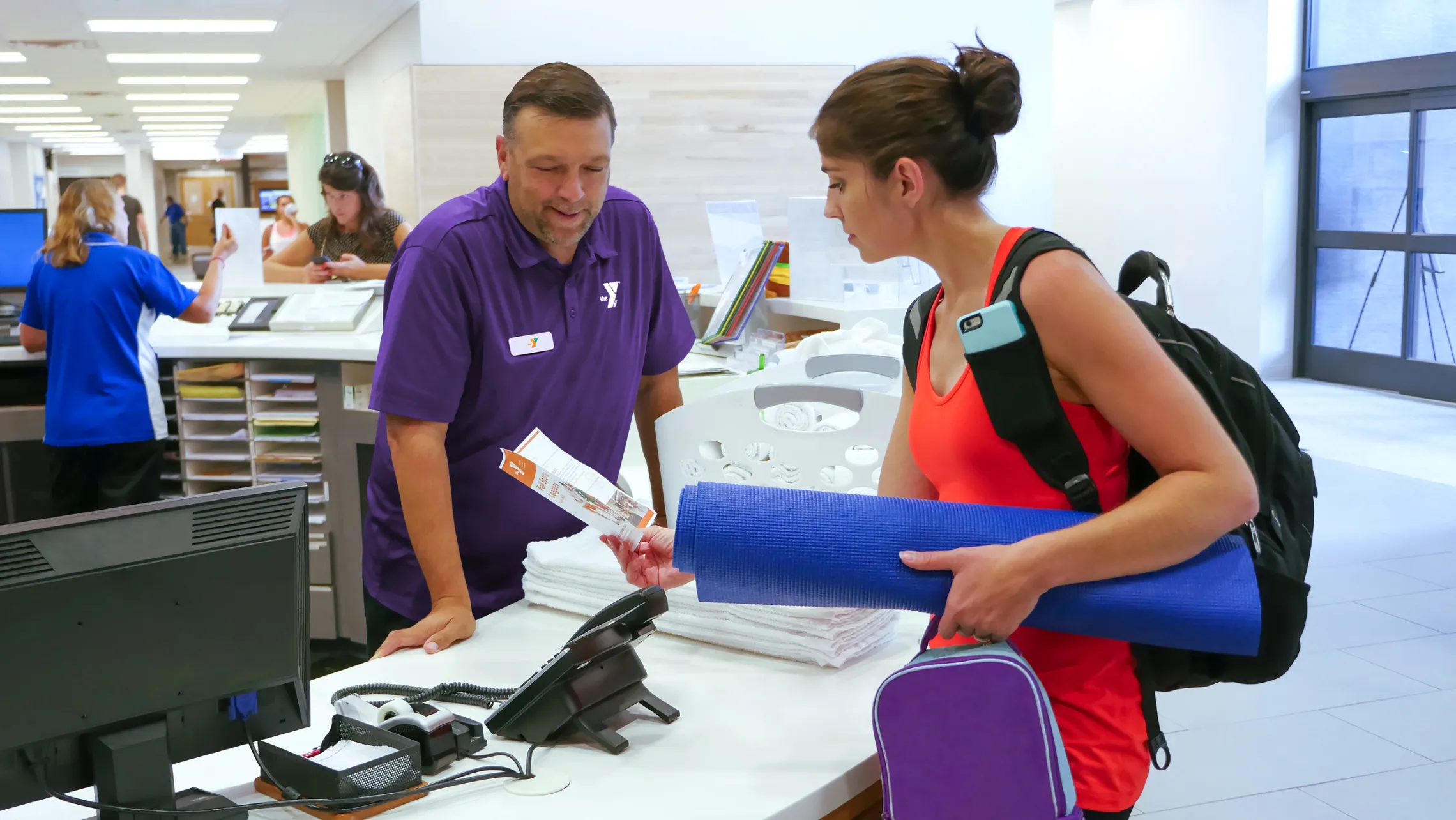 A woman talks to a man at a front desk