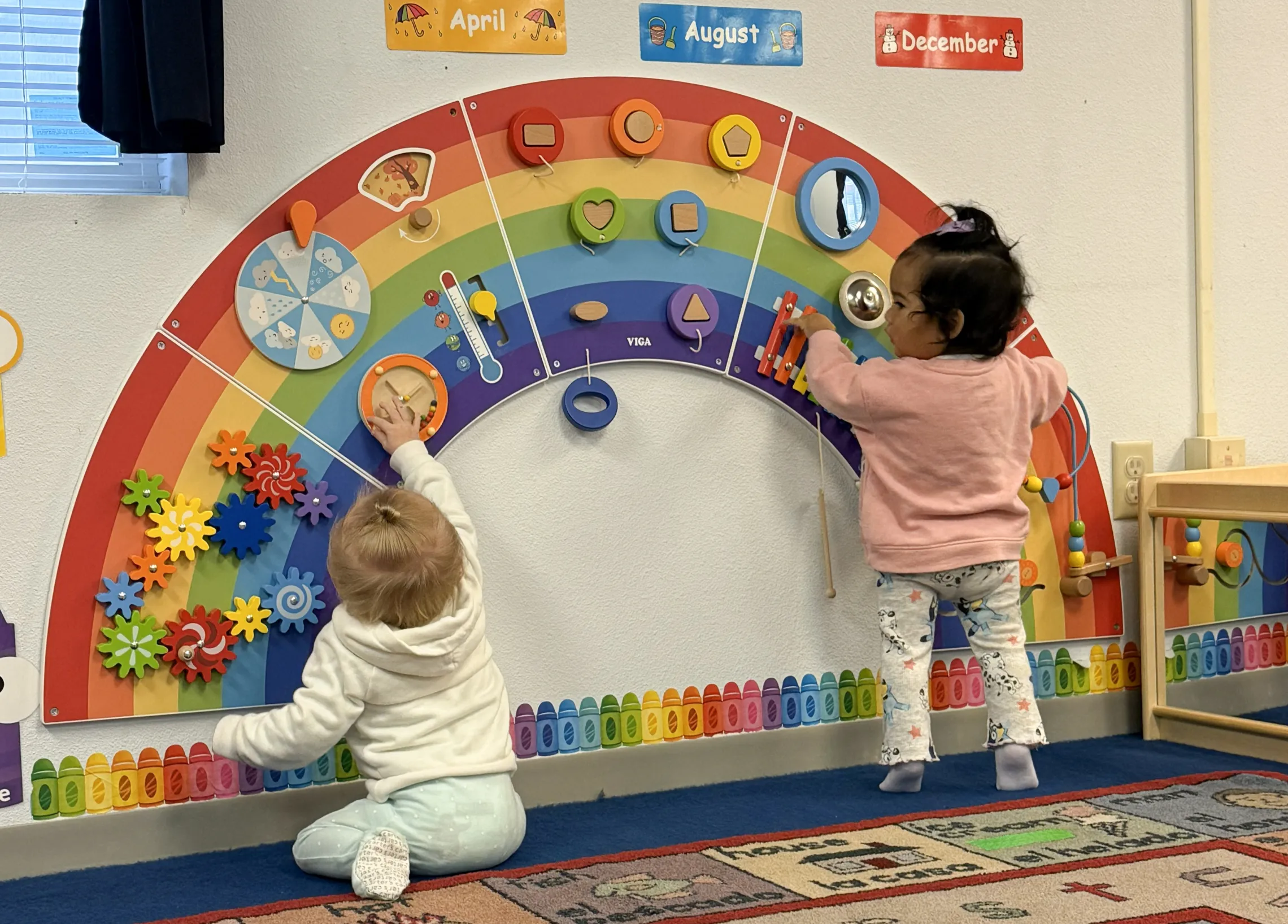 Two toddlers playing with an interactive toy wall