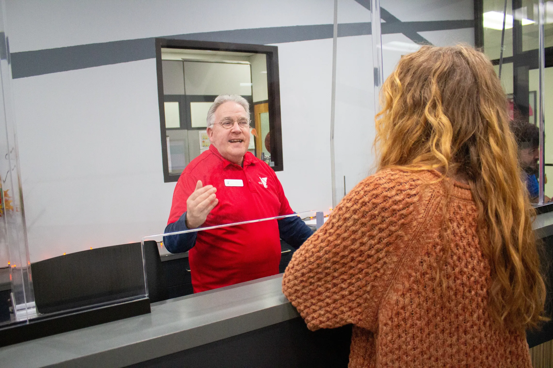 A woman talks to a man at a front desk