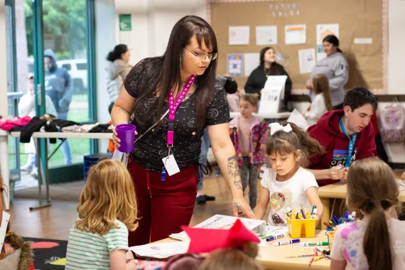 A woman looks over art made by a young girl 