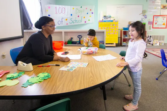 A woman at a table talks to a young girl