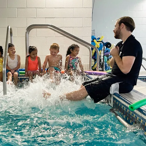 A swim class splashing their feet in the water