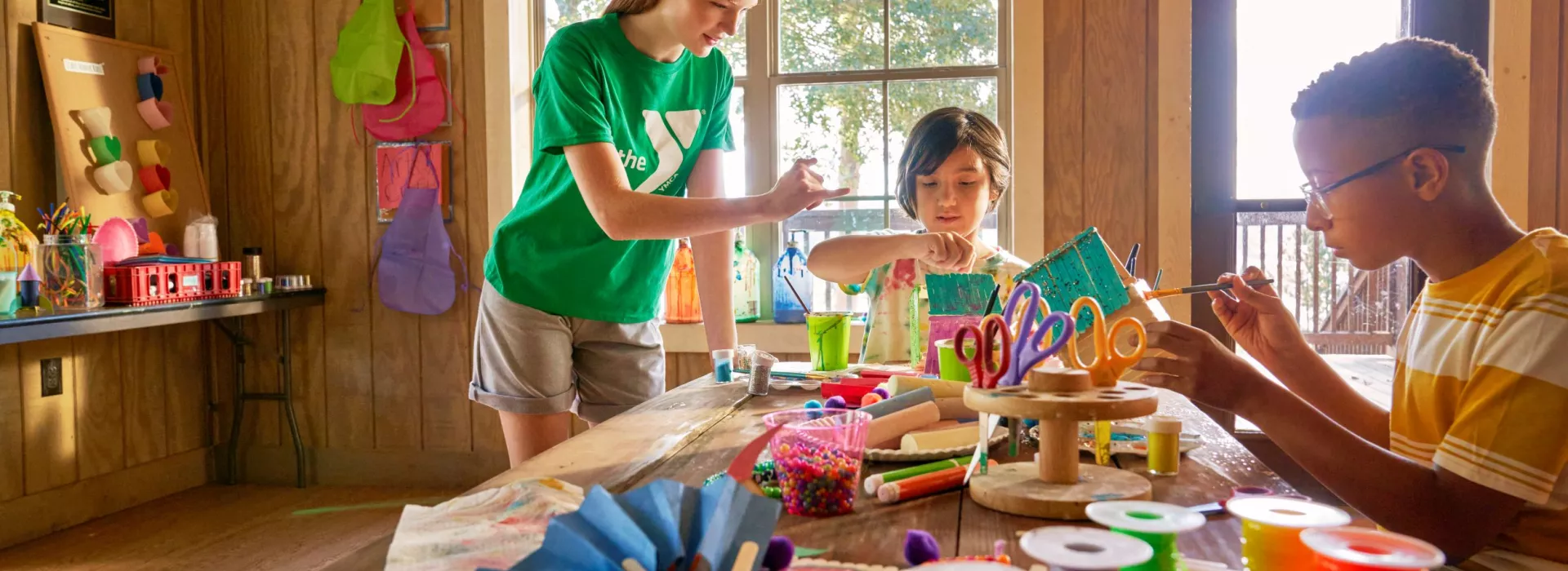 Youth painting birdhouses in an art room.