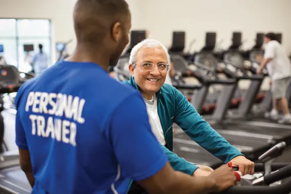 Person on treadmill is assisted by a personal trainer