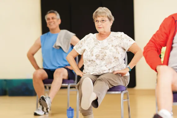 A group of people doing a chair group exercise 